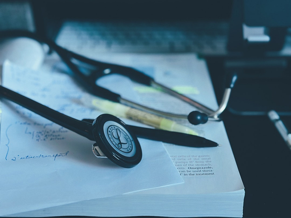 A Stethoscope laying on paper and a textbook